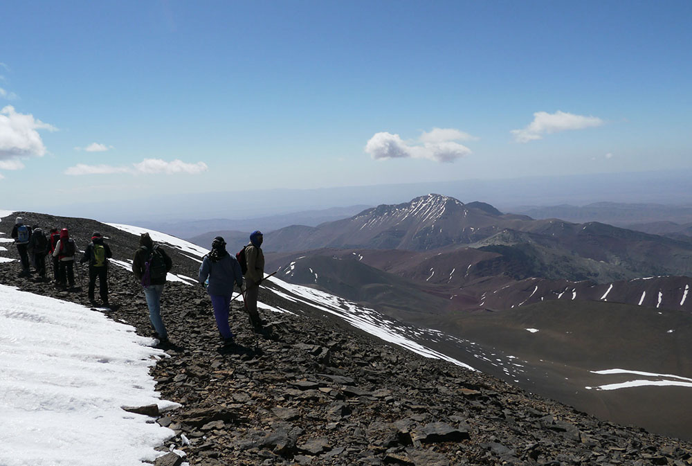 Des randonneurs contemplent le paysage lors de l'ascension du M'Goun : des collines rocailleuses saupoudrées de neige.