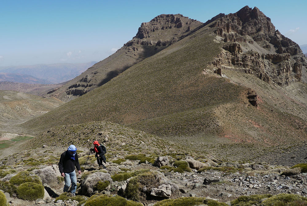 Deux randonneurs au pied d'imposantes collines rocailleuses lors du séjour Ascension du M'Goun